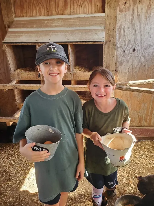 Children learning animal care with feed buckets in the barn